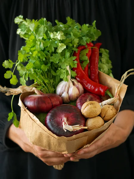 Fresh vegetables decorated in a bouquet. Female hands holds a bouquet of fresh vegetables. Black background. Harvesting. Close-up.