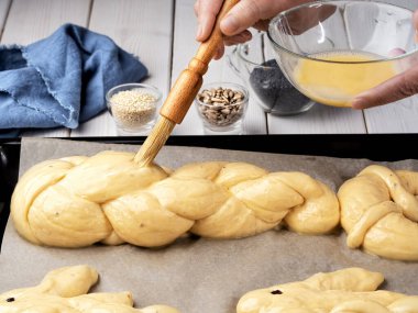 Paskalya çörekleri, challah, tavşan şeklinde çörekler. Fırına yerleştirmeden önce pişirme denemesi. Pişirmeden önce tereyağlı çöreklerle fırçala. Yakın plan. Örülmüş tatlı ekmek hamuru.