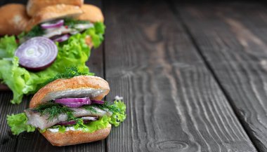 Geleneksel Hollanda sandviçi, ringa balığı ve siyah ahşap masada sebzeli. Norveç 'te geleneksel sokak yemekleri. İsveç yemeği. Yakın çekim, alan derinliği. Metin için kopyalama alanı.