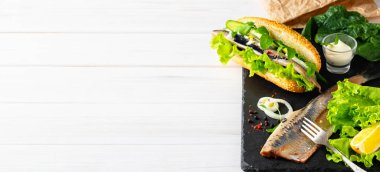 Soğanlı, salatalıklı ve salatalı fileto sandviçi yapıyorum. Fotokopi alanı olan beyaz ahşap arka plan. Norveç ve İsveç 'te geleneksel sokak yemekleri. İskandinav mutfağı