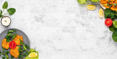 Açık gri bir sırt çanağında gri bir tabakta vegan hamburgerler için sebze köfteleri ya da pirzola. Bir tabağın yanında sos ve balkabağı dilimleri. Üst görünüm, alanı kopyala