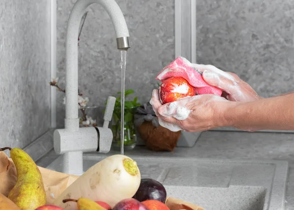 Woman thoroughly washing fruits and vegetables after shopping at the store. The concept of personal hygiene in detail, the fight against viruses and bacteria. Close-up, health care