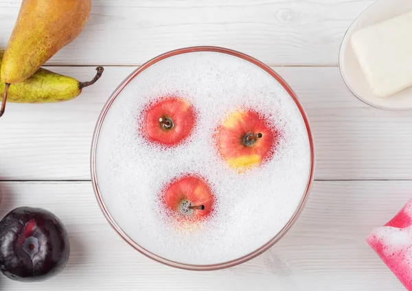 Washing fruits in a cup with foam after purchase, flat lay. Wash fruits after purchase to eliminate viruses, infections, and dirt.