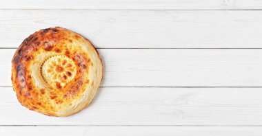 Beyaz ahşap arka planda taze, lezzetli bir tandoor ekmeği. Metin ya da tarif için kopyalama alanı olan düz konum. Orta Asya ve Orta Doğu 'da geleneksel ekmek.