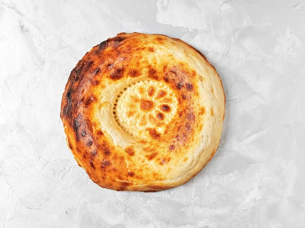 Gri bir masada taze, lezzetli bir tandoor ekmeği. Pankart için üst görünüm ya da düz yatış. Orta Asya ve Orta Doğu 'da geleneksel ekmek.