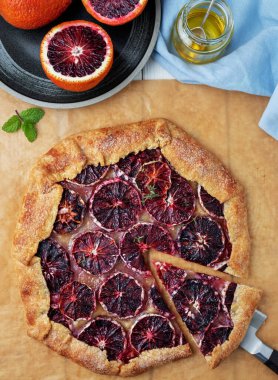 Kırmızı Sicilya portakalları, şeker ve kekik ile galette. Galette, bir parça nane ile süslenmiş, kabartma kağıdının üzerinde yer almaktadır. Lezzetli ev yapımı tatlı. Yaklaş, tahta beyaz arkaplan