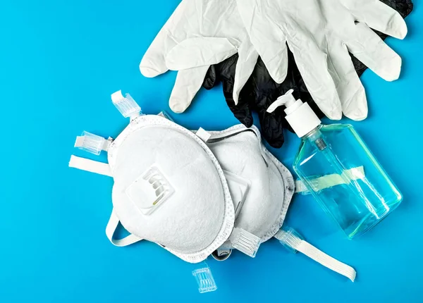 Respiratory protection respirator and latex gloves, antiseptic gel - personal protective equipment, provide protection against the spread of infection. Top view, bright blue background