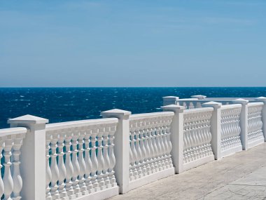 Klasik Roma yapımı beyaz beton parmaklıklar terastaki binanın dışında ya da deniz manzaralı deniz manzaralı ve arka planda bulutlar var. Kopyalama alanı ile yakın plan.