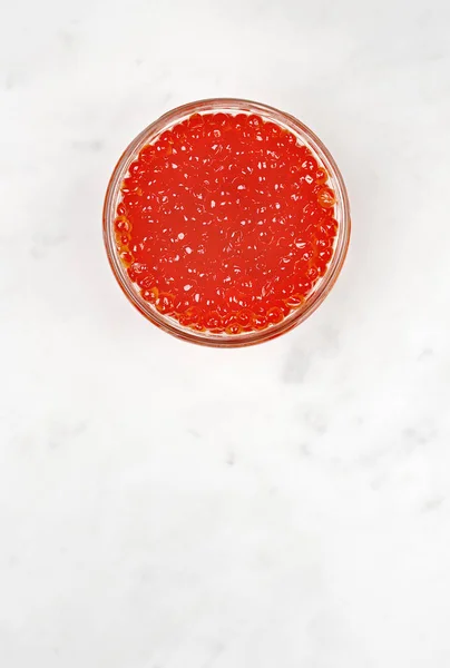 Tigela com caviar vermelho em uma mesa de mármore — Fotografia de Stock