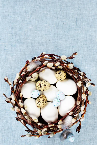 Easter decoration with blooming willow branches and colorful eggs in a basket — Stock Photo, Image