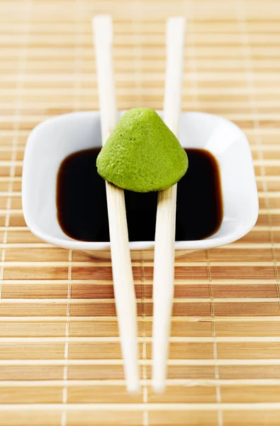 Sada wasabi a sojové zdroj na bambusové ubrus s dřevěnými hůlkami. — Stock fotografie