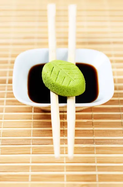 Conjunto de wasabi y fuente de soja en un mantel de bambú con palillos de madera . —  Fotos de Stock