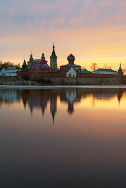 Staraya Ladoga, erkeklerde Saint Nicholas Manastırı görüntülemek Volkhov nehir bir bankadan günbatımında.
