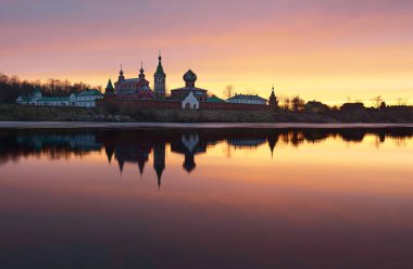Staraya Ladoga, erkeklerde Saint Nicholas Manastırı görüntülemek Volkhov nehir bir bankadan günbatımında.