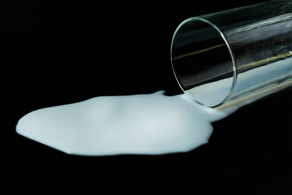 Siyah arka planda dökülen bir bardak süt..