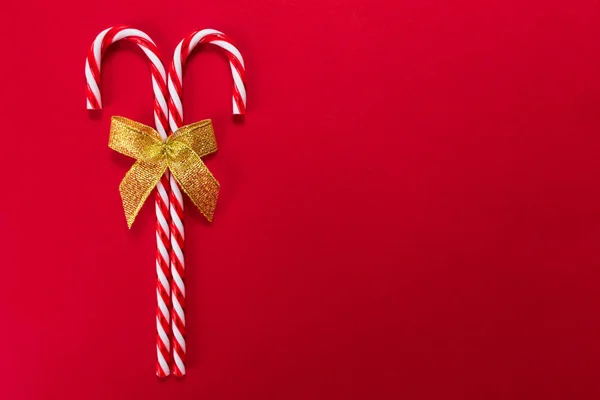 Twee Kerststokjes Met Gouden Strik Rode Achtergrond Kopieerruimte — Stockfoto