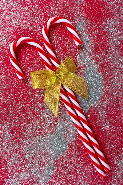 Twee Kerstsnoepjes Met Een Gouden Strik Een Glanzende Rode Achtergrond — Stockfoto