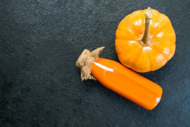  Şişede balkabağı suyu ve siyah arka planda bir balkabağı. Yukarıdan bak. Boşluğu kopyala.