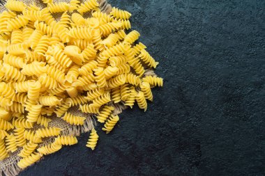  Siyah arka planda çiğ makarna. Boşluğu kopyala.