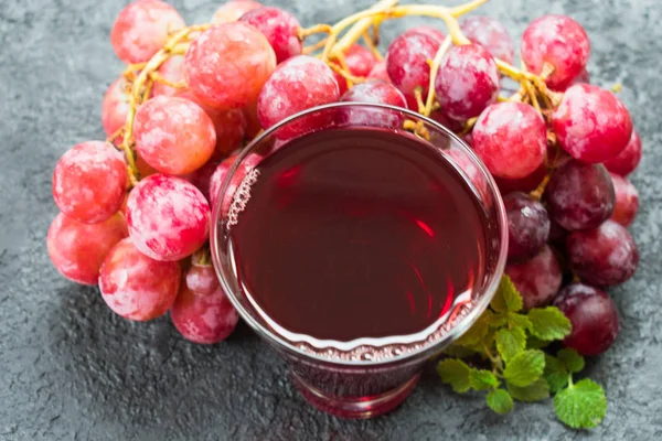 Glass of grape juice and a branch of grapes on a black background. View from the top.