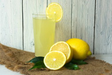 Beyaz ahşap arka planda bir bardak limon suyu ve limon. Vitamin içeceği.