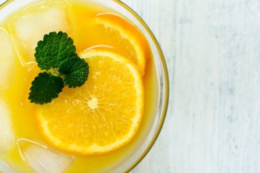 Beyaz ahşap arka planda buzlu ve naneli bir bardak portakal suyu. Üst Manzara. Yakın plan..