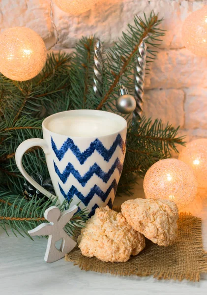 Coconut macaroons and a cup of milk on the background of Christmas decorations.