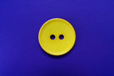 Mavi arkaplanda izole edilmiş büyük sarı düğme.