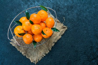  Siyah arka planda vazoda yaprakları olan bir sürü mandalina. Düz yatıyordu. Boşluğu kopyala.