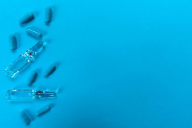 İğne için ampuller ve açık mavi arka planda bir sürü mavi kapsül. Boşluğu kopyala.