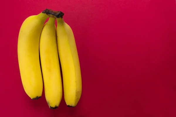 Τρεις Μπανάνες Απομονωμένες Κόκκινο Φόντο Αντιγραφή Χώρου — Φωτογραφία Αρχείου