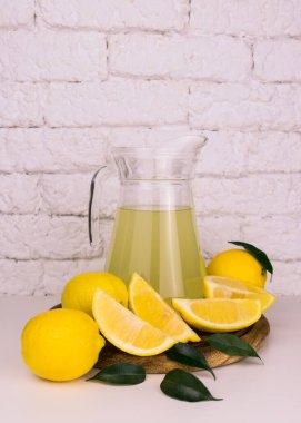 Limonlu sürahi ve olgun limonlu beyaz bir arka plan. Uzayı kopyala Dikey yerleşim.
