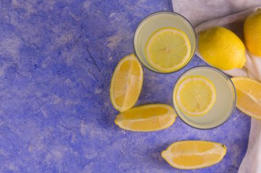 Açık mavi arka planda doğal limon suyu ve taze limon. Düz yatıyordu. Boşluğu kopyala.