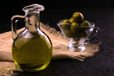  Siyah bir arka planda zeytinyağı ve arka planda soslu zeytin yağı. Zeytin yağı kavramı.