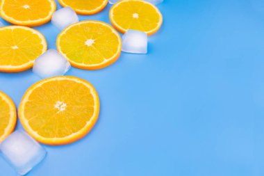 Mavi arka planda portakal dilimleri ve buz küpleri. Boşluğu kopyala.