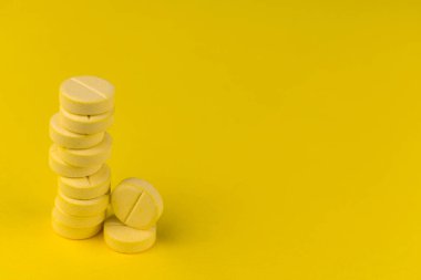 Sarı arkaplandaki C vitamini tabletleri. Boşluğu kopyala.