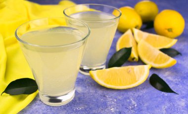 İki bardak limon suyu ve açık mavi arka planda taze limon. Yakın plan..