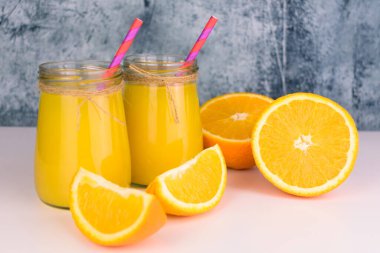  Masada iki portakal suyu, cam kavanozlar ve taze portakallar var. Yakın plan..