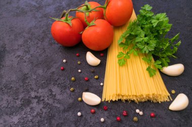 Spagetti. Siyah arka planda makarna için malzemeler. (domates, otlar, baharatlar, sarımsak). Boşluğu kopyala.