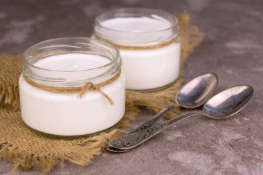 Gri arka planda iki kavanoz organik ekşi krema..