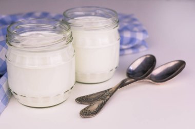 Beyaz bir masada iki kavanoz Yunan yoğurdu. Yakın plan..