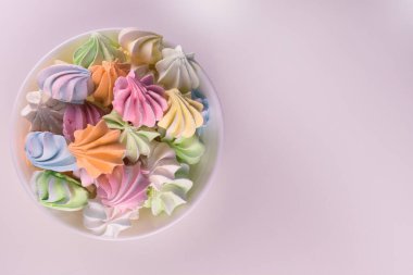 Beyaz arka planda bir tabakta çok renkli küçük kremalar. Yukarıdan bak. Boşluğu kopyala.