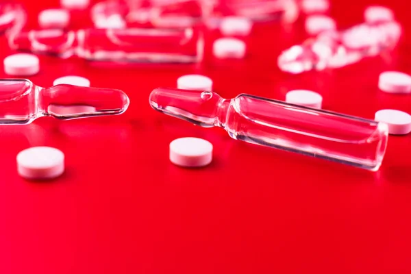 注射用のアンプルと赤い背景の白い錠剤 医学的背景 スペースのコピー — ストック写真