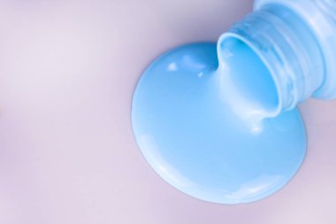 Beyaz arka planda bir şişeden akan açık mavi boya. Boşluğu kopyala