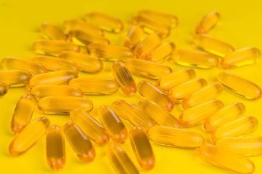Sarı arka planda balık yağı kapsülleri. Yakın plan..