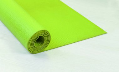 Tahta beyaz zeminde yeşil yoga minderi.