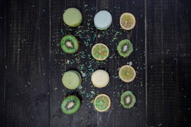 Kivi, portakal ve limon bir ahşap gark tablo sırayla ile yeşil ve beyaz macaroons