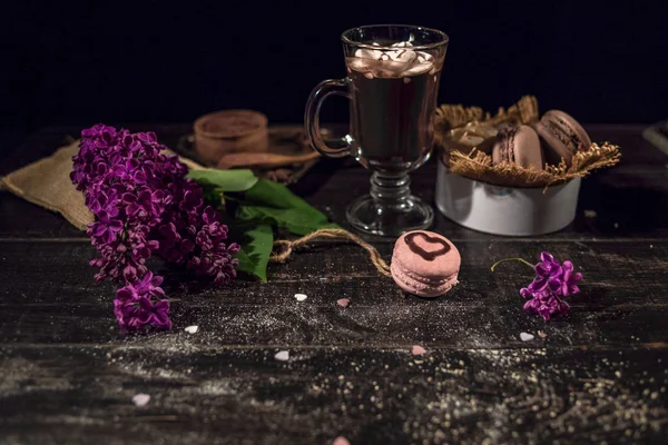 Hot cocoa with marshmallow on a wooden table with a lilac branch