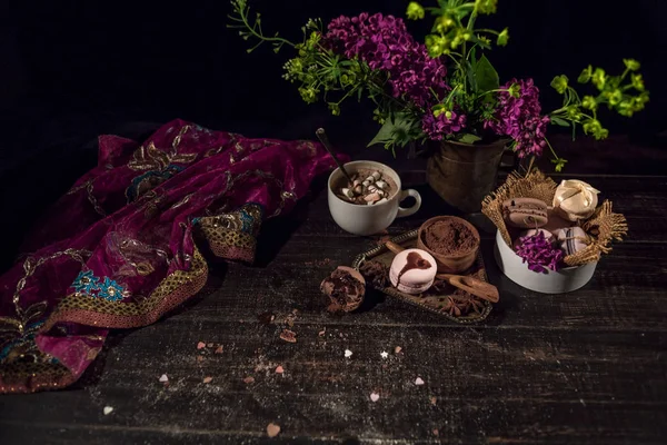 Bir eski akan mor şeffaf eşarp oryantal tarzı ahşap bir masada kahve ve bakır bir dokuma vazoda macaroons.