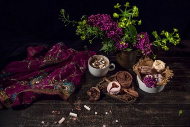 Bir eski akan mor şeffaf eşarp oryantal tarzı ahşap bir masada kahve ve bakır bir dokuma vazoda macaroons.
